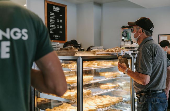 A man wearing a mask ordering pies at the counter of Fairlie Bakehouse.