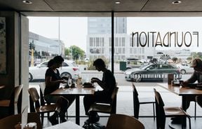 Two people eating at a table in front of a window.