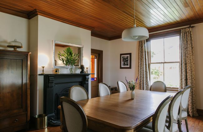 Dining room with table and original fireplace at French Bay House, Akaroa Canterbury.