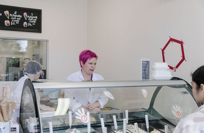 Woman helping customer choose gelato.