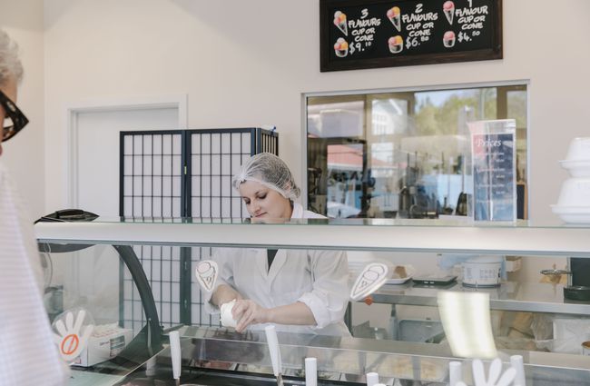 Woman serving behind the gelato counter.