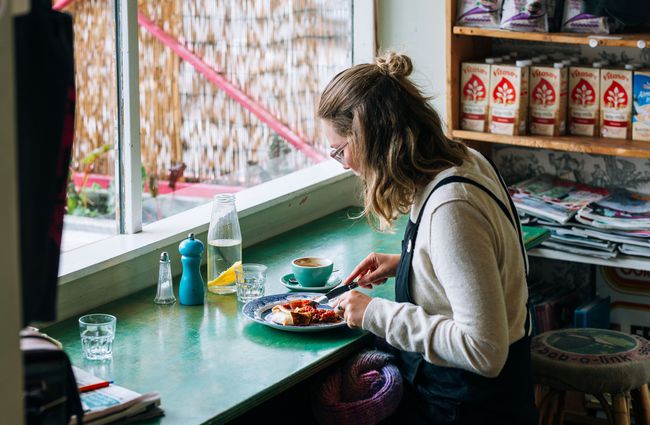 A woman eating at a counter by the window inside Gispy Kitchen cafe Wellington.