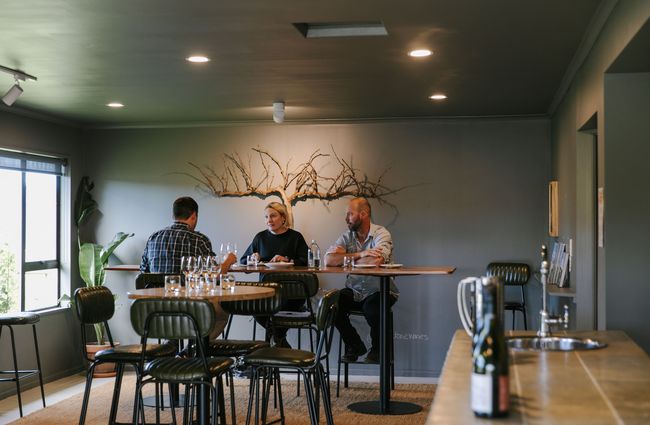 Customers sitting on a leaner table drinking wine at Greystone Wines, North Canterbury.