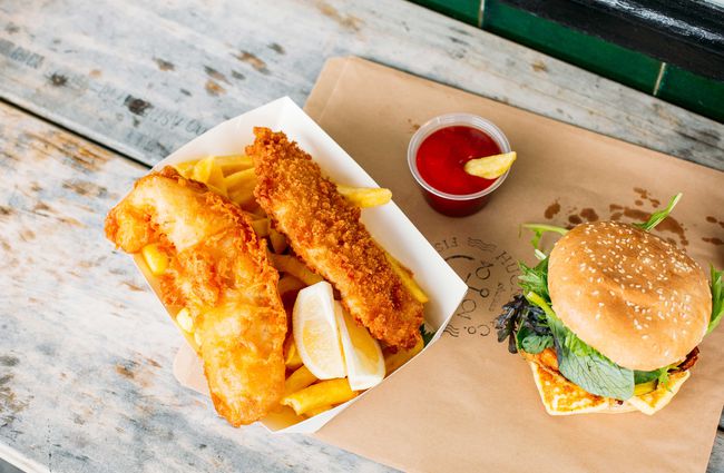 A flatlay of fish and chips on a wooden table.