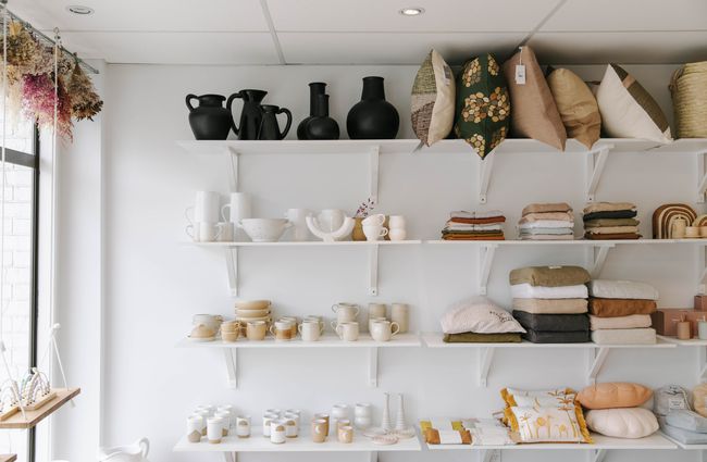 Shelves filled with homewares including pottery and cushions.