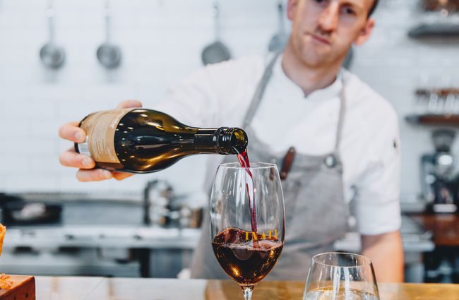 Wine being poured into a glass by a chef inside Inati restaurant Christchurch, New Zealand.
