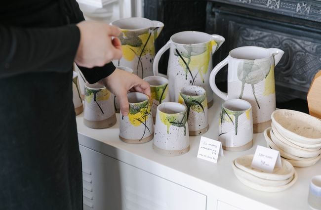 Close up of customer looking at ceramic cups and jugs Inc. Design in Ōamaru.