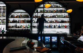 Man up a ladder retrieving bottle of spirits at Itch Wine Bar, New Plymouth.