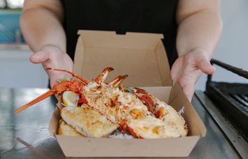 Takeaway box with cooked crayfish dish inside.