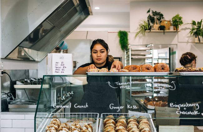 Woman rearranging donuts on display at Knead Artisan Donuts, New Plymouth.