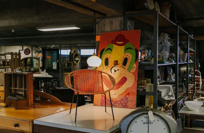 Vintage chair with retro painting of clown's face behind it at La Voute, Christchurch.