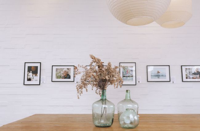 Photography framed on the wall with dried flowers in glass jars on the table below at Little Rosie, Auckland.