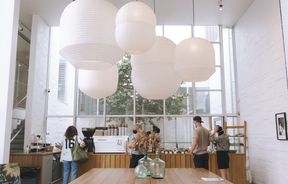 Large wooden tables with pendant paper lanterns above at Little Rosie, Auckland.