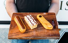 Man holding wooden board with three french pastries from Louis by Louis Sergeant in Porirua.