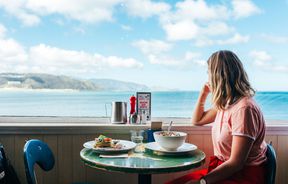 A woman looking out towards the ocean from a seat inside Maranui cafe Wellington.
