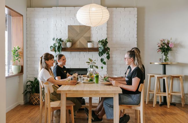 Four women chatting and smiling around a table at Mint Folk and Co in Twizel.