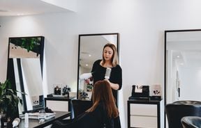 A woman blow drying hair inside Mod's Merivale hairdresser in Christchurch.