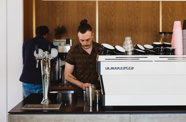 Man works behind a coffee machine.