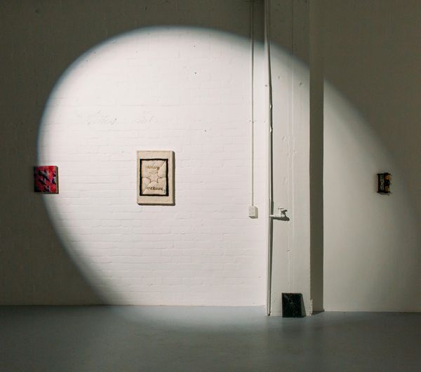 A spotlight shining on a wall of two small art works.