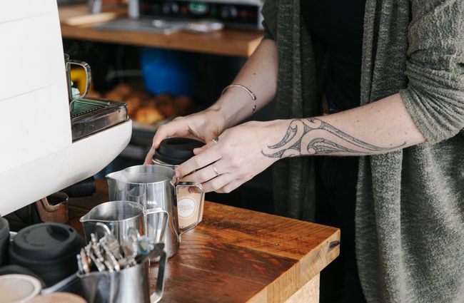 Barista putting a lid on reusable coffee cup.