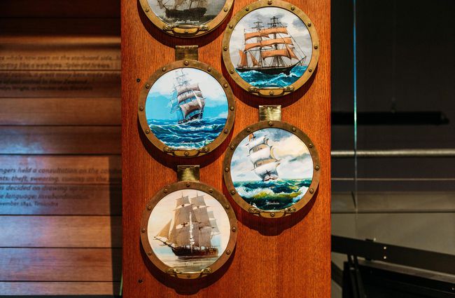 Close up of pictures of sail boats on a wall.