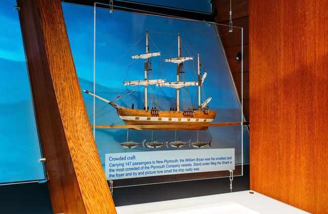 A sail boat model on display behind a glass screen.