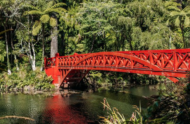 A red bridge across a pond.