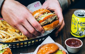 Hands holding a burger.