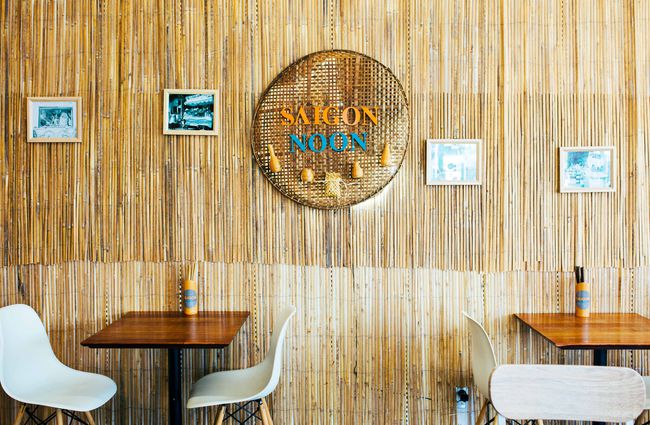 Two tables inside with Saigon Noon sign on the wall.