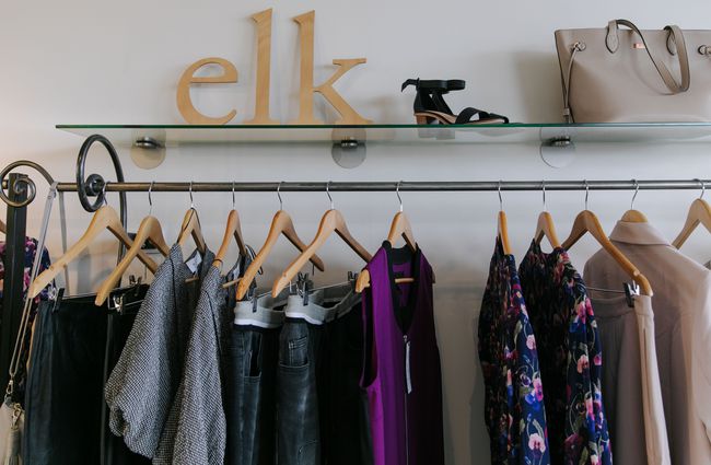 Rack of clothing with Elk wooden letters on a shelf.