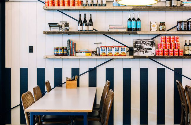 The blue and white striped walls inside State Pasta with shelves of Italian pantry goods displayed above.
