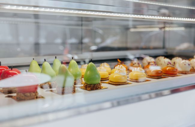 Rows of fine pastries in a white and glass cabinet.