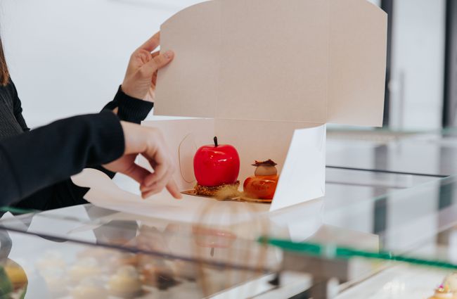 Shiny red apple pastry in a white box.