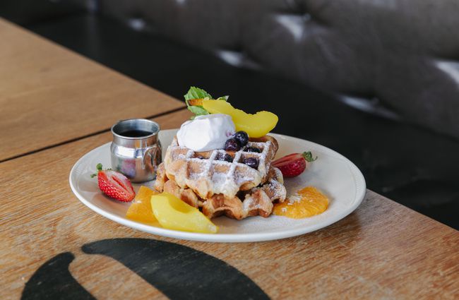 Close up of waffle with cream and fruit.