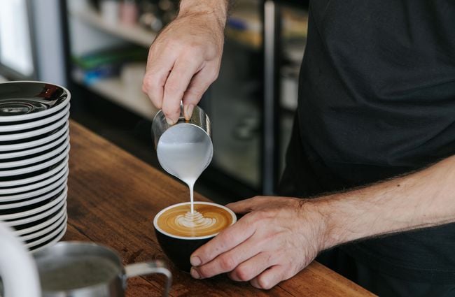 Man making a flat white with steamed milk.