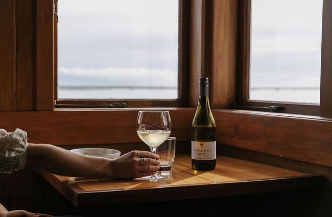 Woman holding a glass of white wine at Boat Shed Cafe.