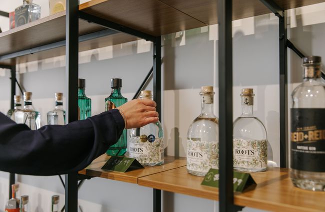 Hand picking a bottle of gin of a shelf at The Juniper Collective, Christchurch.