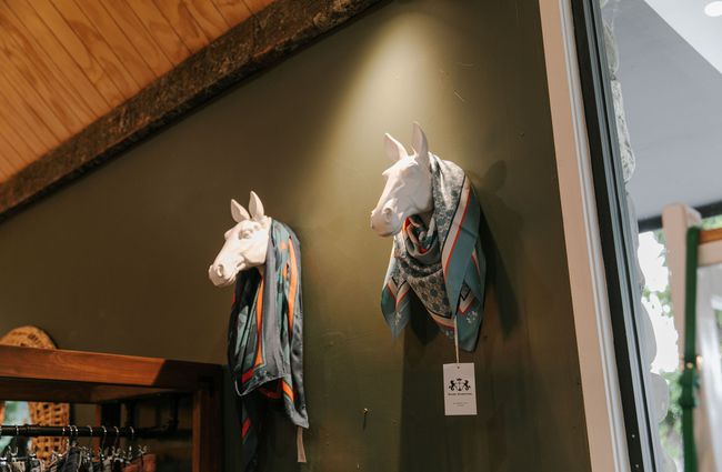 Two white horse heads on a wall covered in silk scarves at The Red Little Fox store in Fairlie.