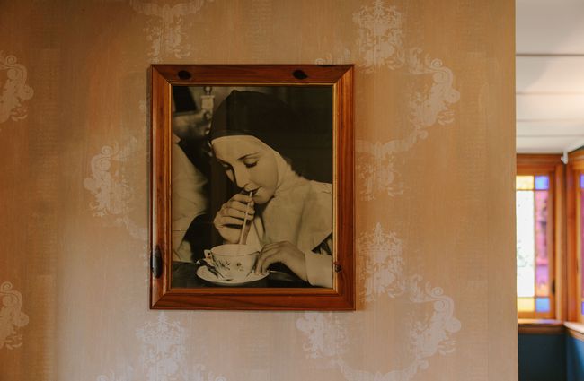 Old photograph of a nun sipping a drink through a straw at The Old Vicarage, Christchurch.
