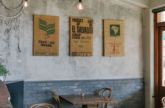 Old coffee bean bags mounted on the wall above table at The Smoking Barrel, Motueka Tasman.