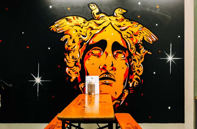 Table with artwork of a face on the wall at Three Sisters Brewing, New Plymouth.