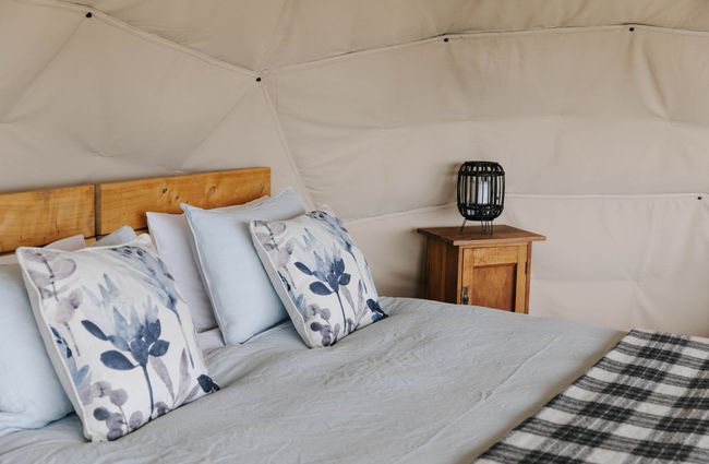 Close up of cushions on the bed inside glamping pod in Waitaki