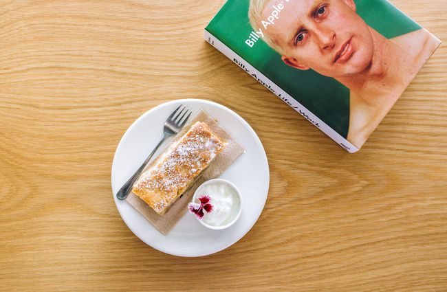 Flatlay image of slice of cake and Billy Apple book at Vic Books', Wellington.