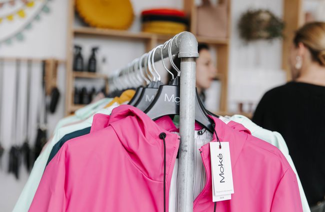 Rack of clothes with pink rain jacket at the front at William Bee in Ōamaru.