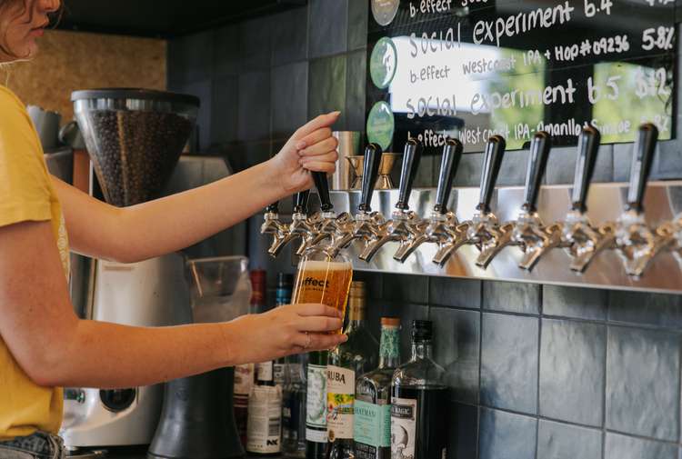 A staff member pulling a pint of craft beer behind the counter at B.Effect in Wanaka.