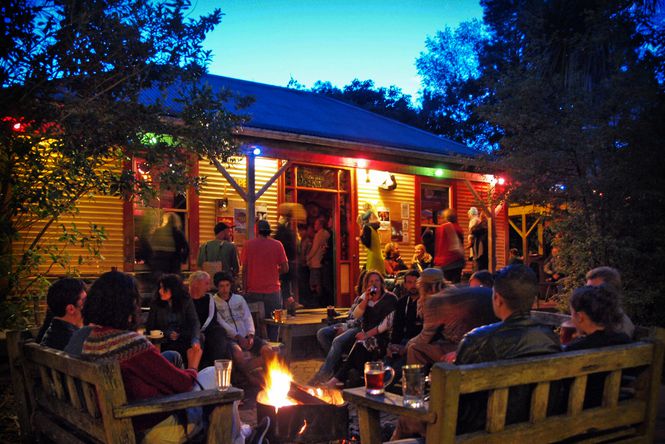 In the courtyard of The Mussel Inn at night time with people gathered around a brazier.