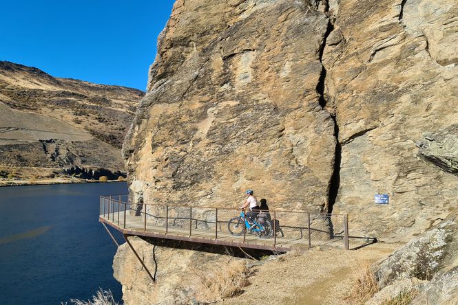 People biking around a cliff face.
