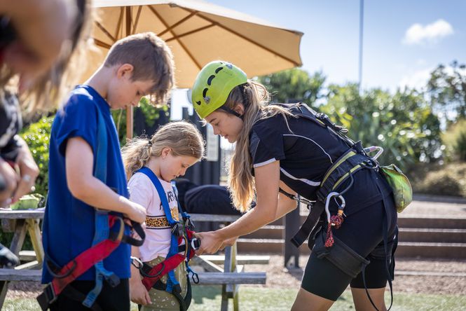 Kids getting harnesses put on them by an instructor.