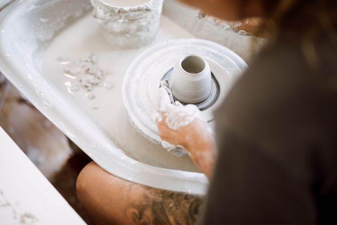 Close up of a cup being made on a pottery wheel.