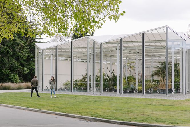 Two people standing outside a large glass house.